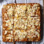 veganer apfelkuchen von oben mit mandeln garniert und in gleichgroße stuecke geschnitten