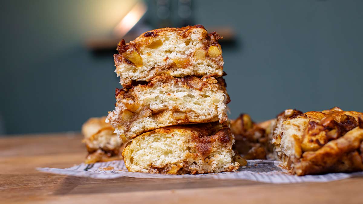 drei stuecke zimtschnecken apfelkuchen gestapelt von vorne auf einem holztisch
