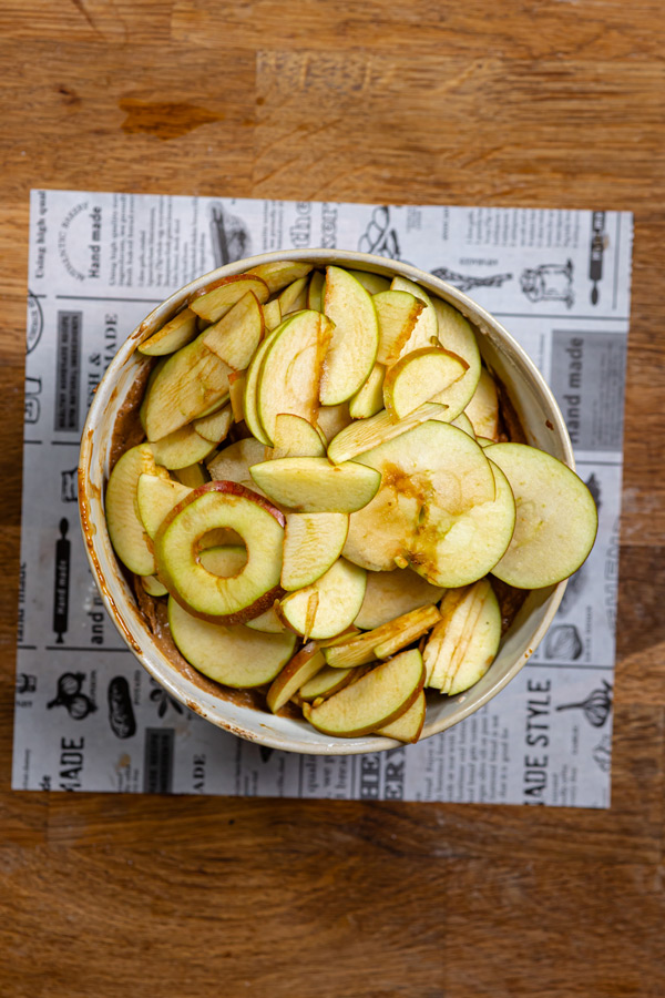 feine apfelscheiben in einer schuessel von oben auf einem holztisch auf weissem backpapier