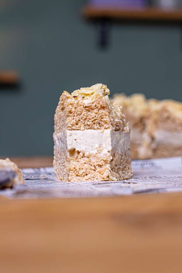 nahaufnahme stueck veganer bienenstich von vorne auf holztisch