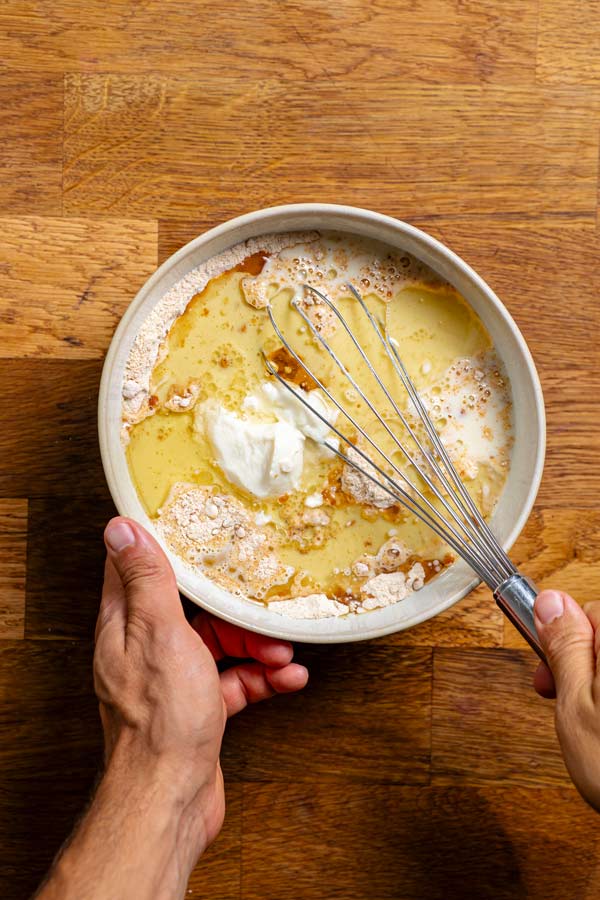 trockene und feuchte zutaten fuer blaubeerkuchen werden mit einem schneebesen in einer schuessel vermengt