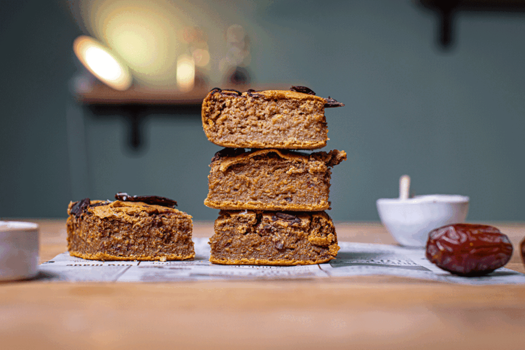 kichererbsen blondies gestapelt von vorne auf einem holztisch mit weissem backpapier