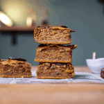 kichererbsen blondies gestapelt von vorne auf einem holztisch mit weissem backpapier