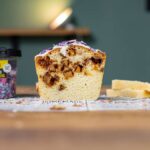 angeschnittener ruehrkuchen mit apfel von vorne auf einem holztisch mit sichtbaren schichten