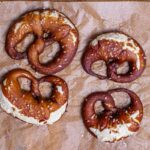 vier brezeln mit dinkel fertig gebacken von oben auf einem backpapier