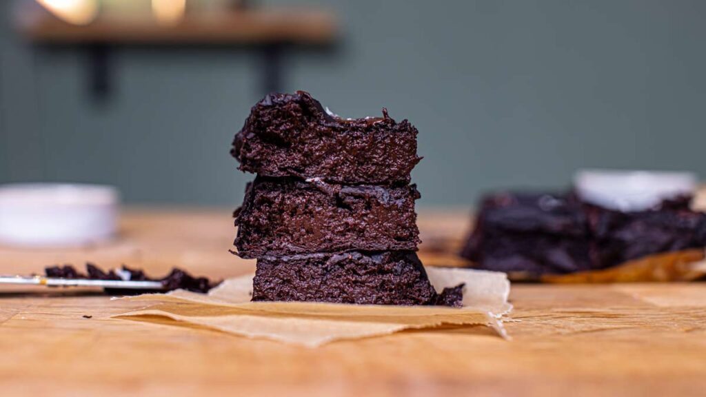 mehrere stuecke suesskartoffel brownies aufeinander gestapelt auf backpapier auf einem holztisch