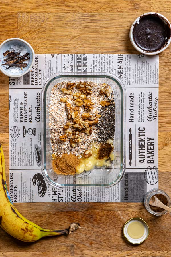 trockene zutaten fuer buchweizen porridge in einem glascontainer von oben auf einem holztisch mit weissem backpapier