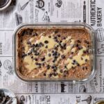 buchweizen porridge angerichtet in einer rechteckigen glasschuessel von oben mit nussmus und blaubeeren garniert