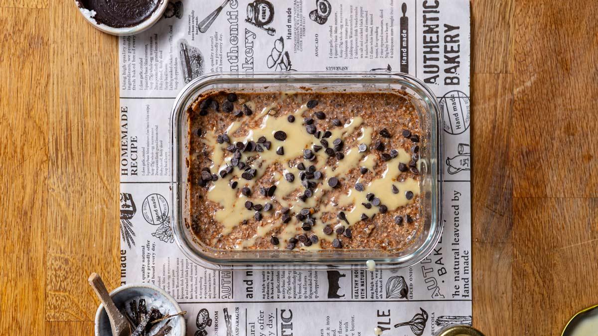 buchweizen porridge angerichtet in einer rechteckigen glasschuessel von oben mit nussmus und blaubeeren garniert