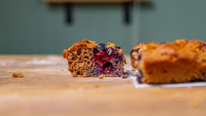 ein stueck herausgeschnittener blaubeer streusel kuchen frontal auf einem holztisch