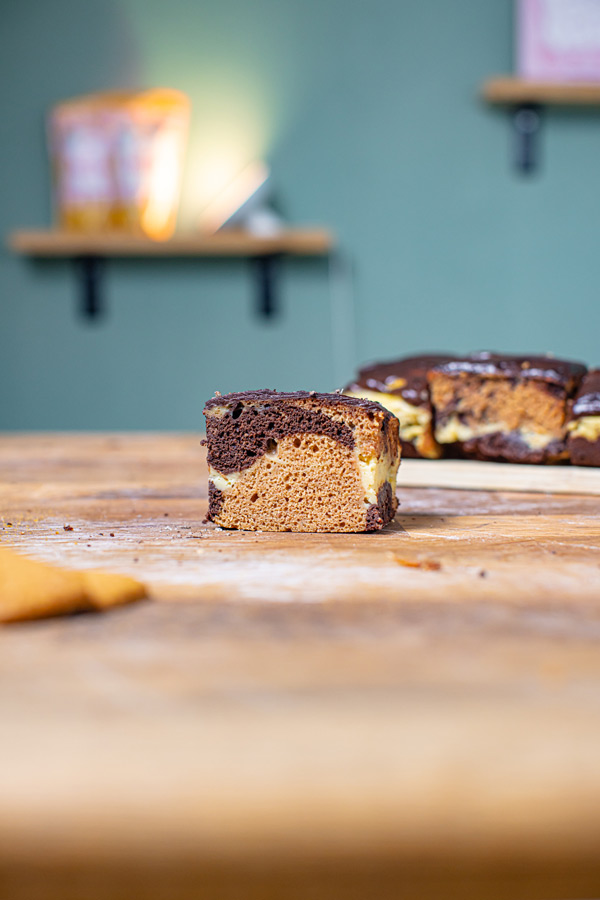 quadratischen stueck gesunder marmorkuchen frontal auf einem holztisch mit deko