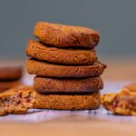 gesunde weihnachtskekse aufeinander gestapelt von vorne auf einem tisch mit weißem backpapier