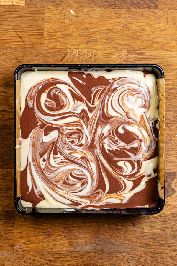 fertig geschichteter donauwellen kuchen in einer quadratischen backform von oben auf einem holztisch