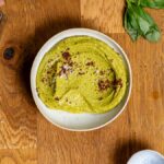 veganer dip in einer weissen schuessel mit paprikapulver garniert von oben auf holztisch mit deko