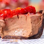 Nahaufnahme eines Stücks Schokoladenkuchen mit frischen Erdbeeren oben.