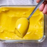 mango eis in eckiger glasschuessel von oben mit loeffel in hand