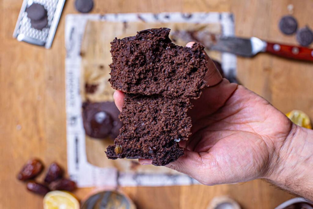 haferflocken brownies in einer hand aufgebrochen von oben über holztisch mit deko