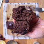haferflocken brownies in einer hand aufgebrochen von oben über holztisch mit deko