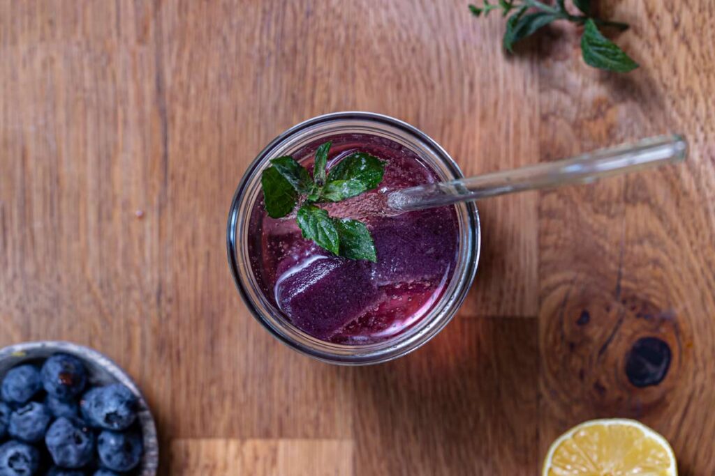 zitronen minze limonade im glas mit strohhalm von oben auf holztisch mit deko