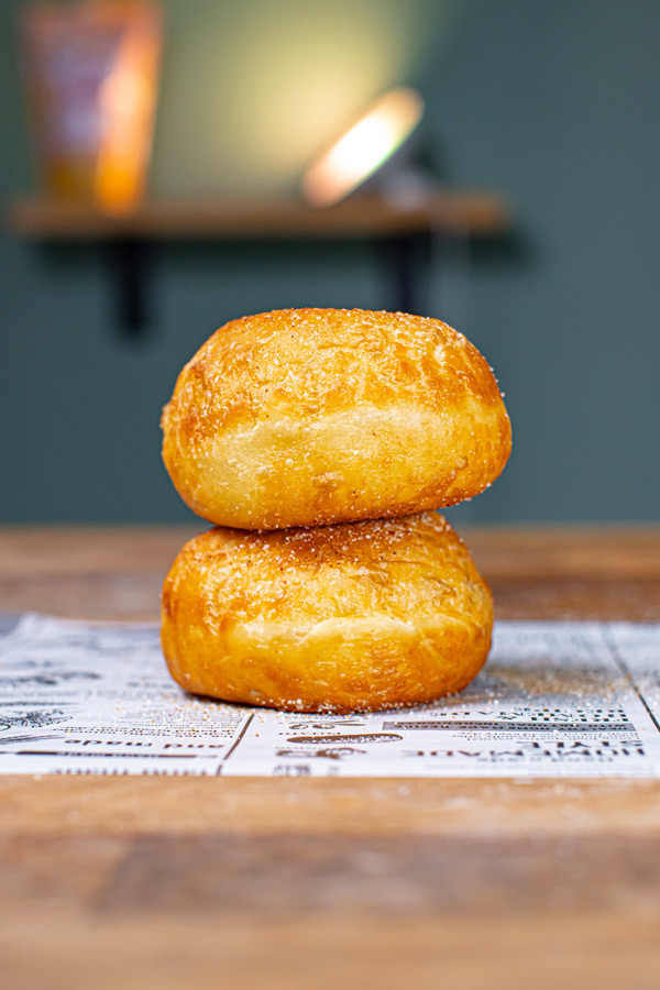 zwei goldbraune zuckerfreie berliner aufeinander gestapelt von vorne auf einem holztisch mit weissem backpapier