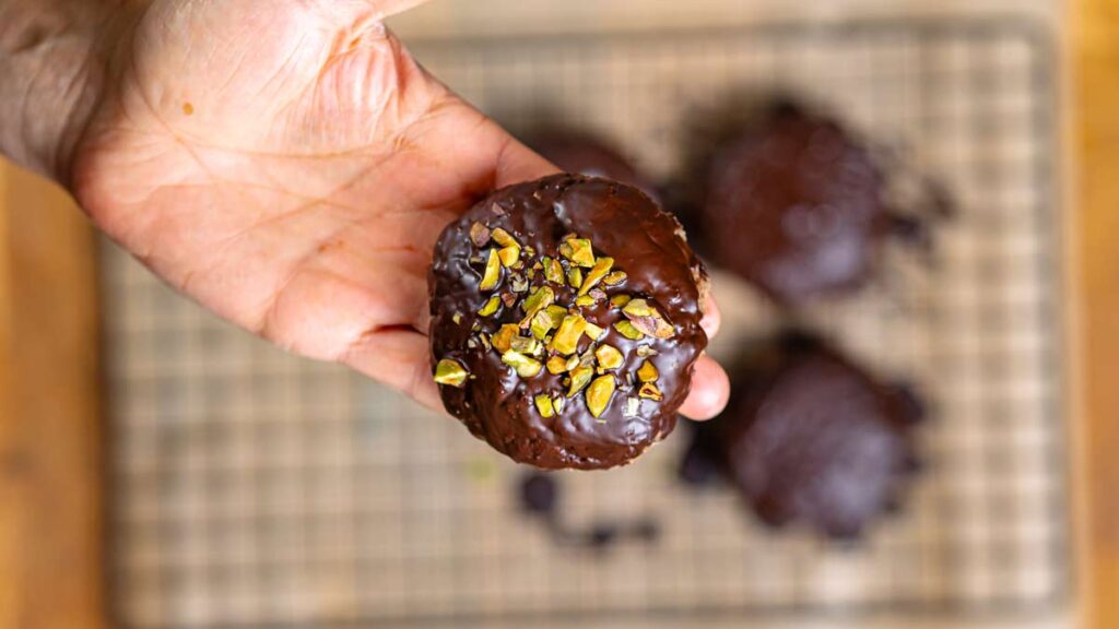 ein elisenlebkuchen in hand von oben nahaufnahme mit weiteren lebkuchen im hintergrund