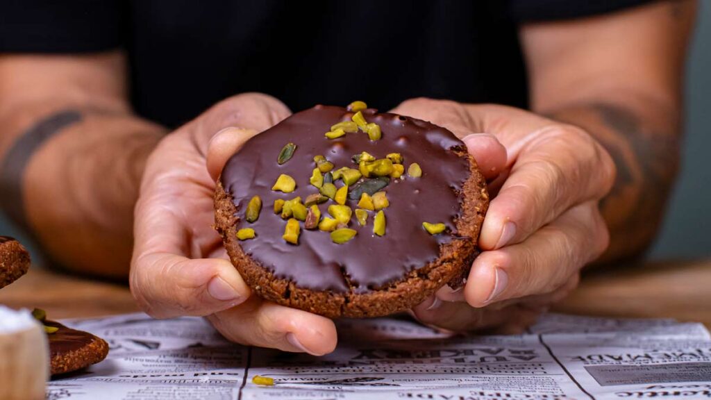 veganer lebkuchen wird in zwei haenden gehalten von vorne mit pistazien garniert