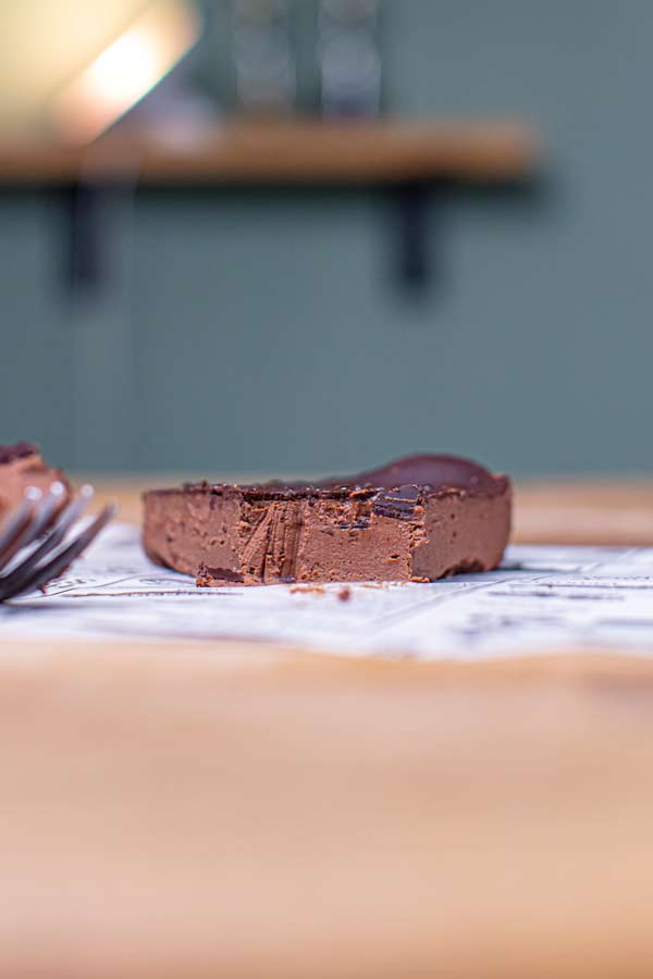 angefangenes stueck schokotarte ohne mehl von vorne auf einem holztisch auf weissem backpapier