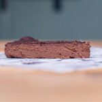 ein stueck schokotarte ohne mehl von vorne auf einem holztisch