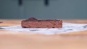 ein stueck schokotarte ohne mehl von vorne auf einem holztisch