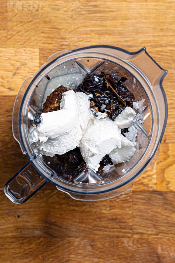 alle zutaten fuer die schokotarte ohne mehl in einem mixbehaelter von oben auf einem holztisch