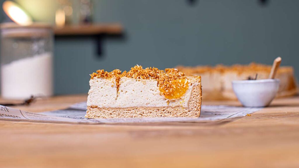 ein stueck mandarine schmand kuchen von der seite auf einem holztisch