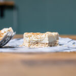 ein stueck milktert von vorne auf einem holztisch mit einem loeffel