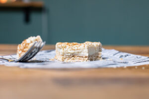 ein stueck milktert von vorne auf einem holztisch mit einem loeffel