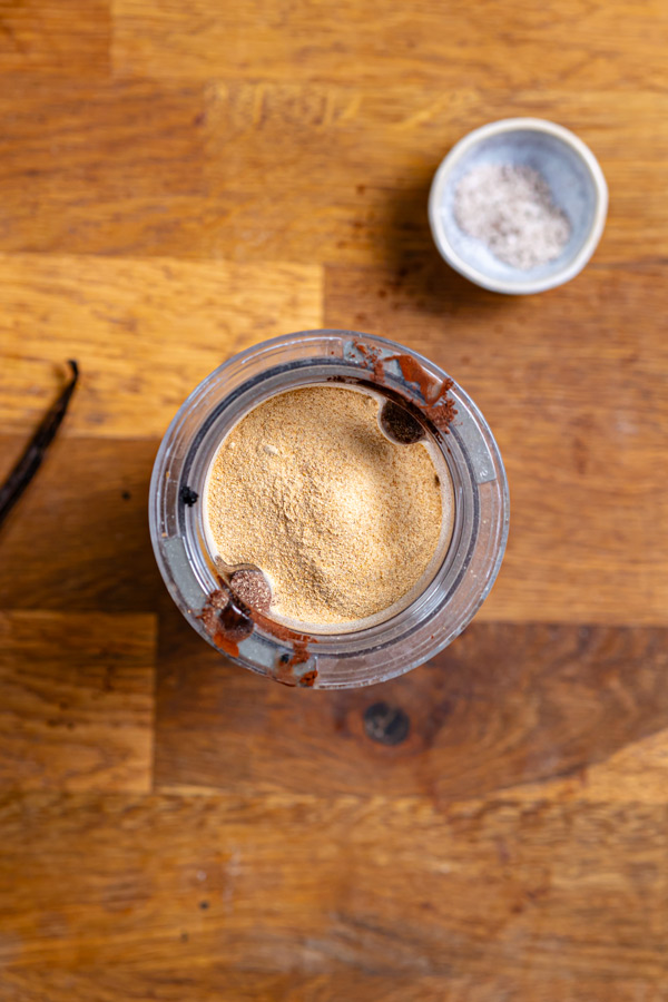 alle zutaten fuer dattel haselnuss creme in einem mixbehaelter von oben auf einem holztisch
