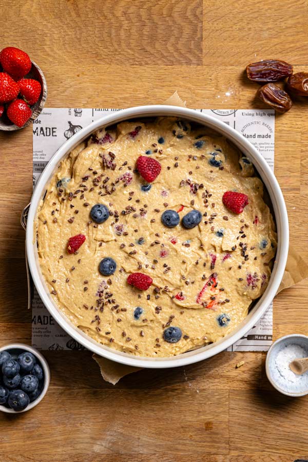 obstkuchen teig in einer springform von oben auf einem holztisch mit deko