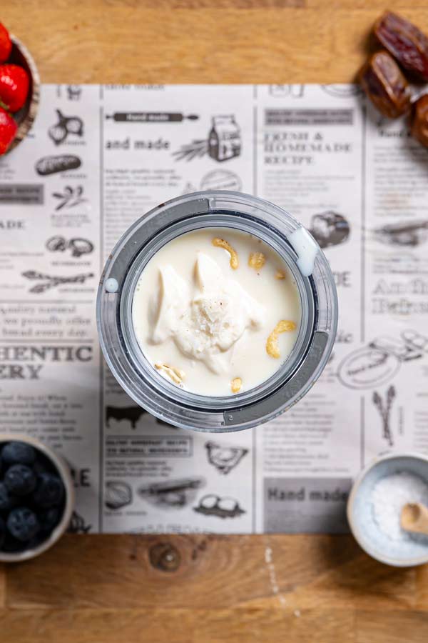 feuchte zutaten fuer obstkuchen von oben in einem mixbehaelter auf einem weissen backpapier mit deko