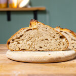 aufgeschnittenes schnelles sauerteigbrot leib frontal auf einem holzbrett auf einem holztisch