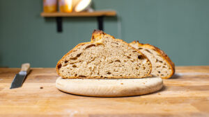 aufgeschnittenes schnelles sauerteigbrot leib frontal auf einem holzbrett auf einem holztisch