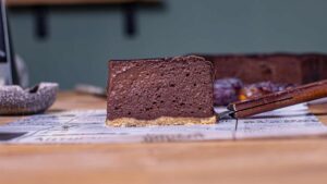 ein stueck schoko schmandkuchen von vorne auf einem holztisch mit dekoration