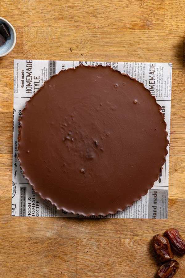 ausgehaertete schokotart in einer form von oben auf einem holztisch auf weissem backpapier