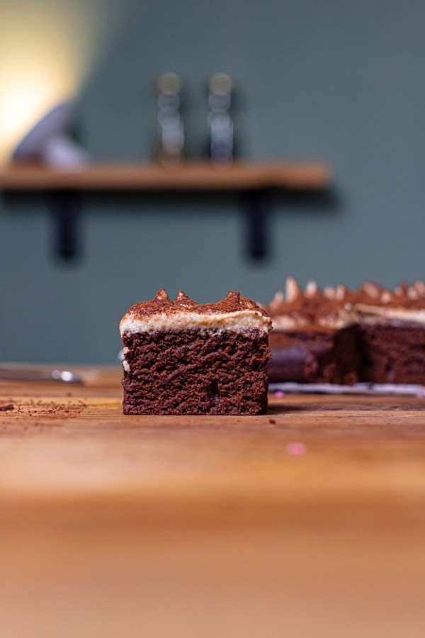 ein stueck gesundes tiramisu mit einer mascarpone und kakaopulver dekoriert auf einem holztisch von vorne