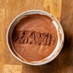schokoladen mousse in einer weissen schuessel von oben auf einem holztisch