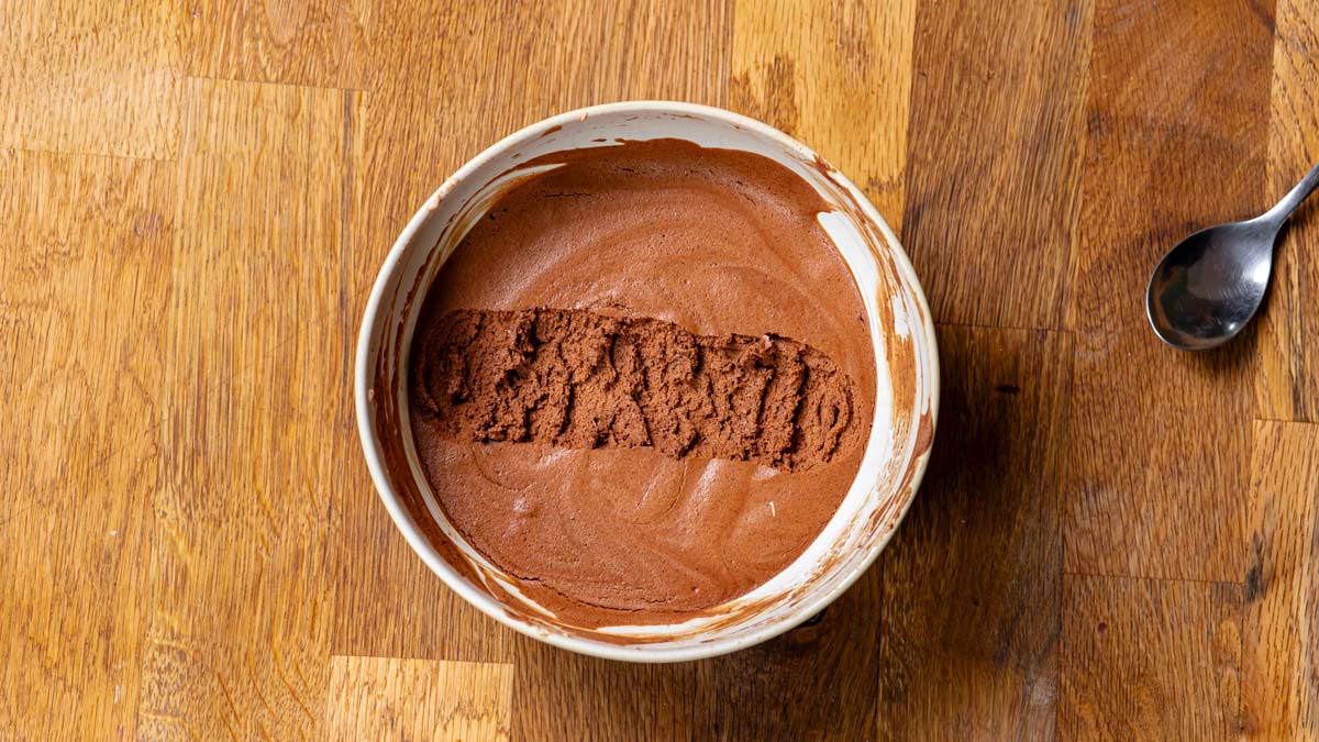 schokoladen mousse in einer weissen schuessel von oben auf einem holztisch