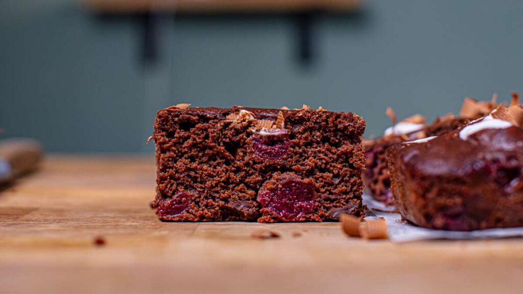 ein stueck schwarzwaelder kirsch kuchen von vorne auf einem holztisch