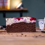 ein stueck gesunde schwarzwaeldertorte von der seite frontal auf einem holztisch