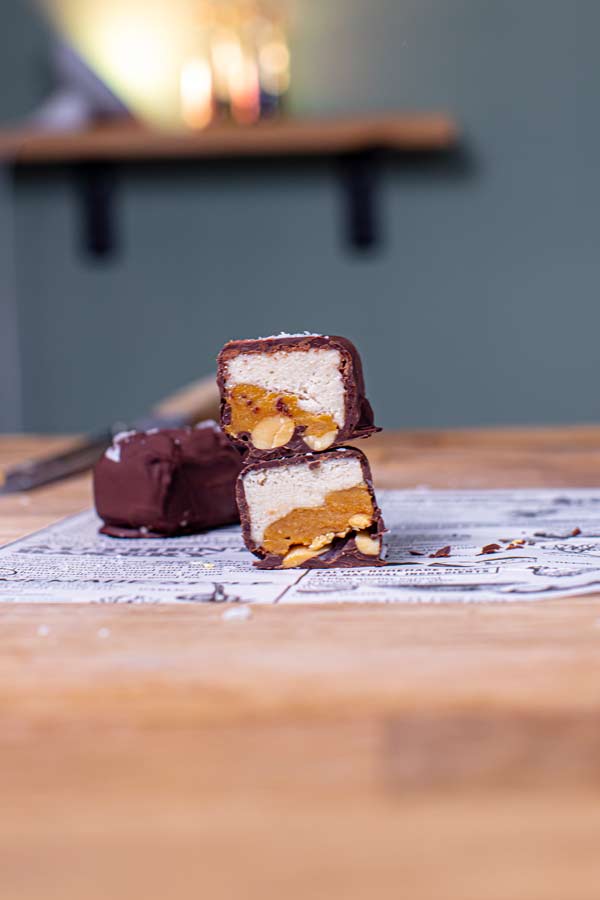 fertiges snickers eis halbiert und gestapelt von vorne vor blau grüner wand