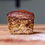 ein stueck baked oats mit banane mit frosting von vorne auf einer holzplatte