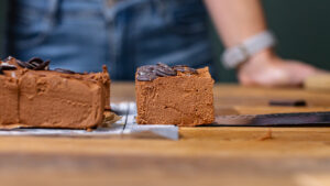 ein herausgeschnittenes stueck brownie ohne mehl auf einem holztisch frontal aufgenommen