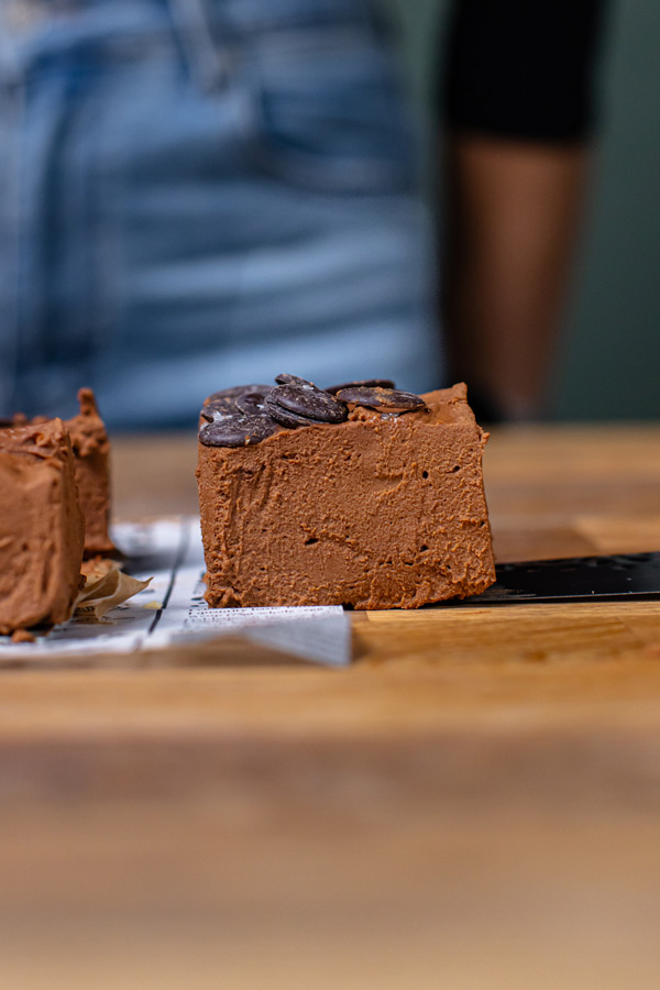 nahaufnahme von einem stueck brownie ohne mehl auf einem holztisch mit schokodrops garniert