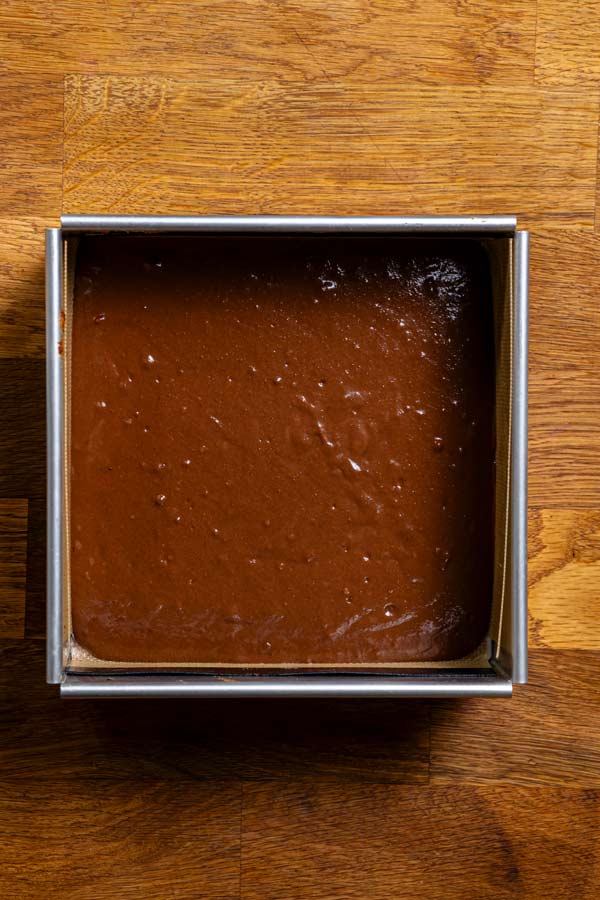 biskuitteig fuer schokotiramisu in einer quadratischen backform von oben auf einem holztisch